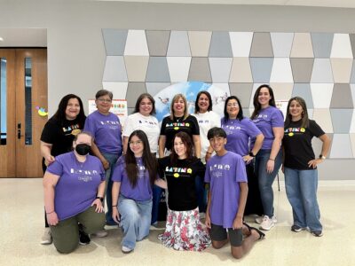 Photo of a group of volunteers posing and smiling wearing the purple the Latina Women's League shirt.