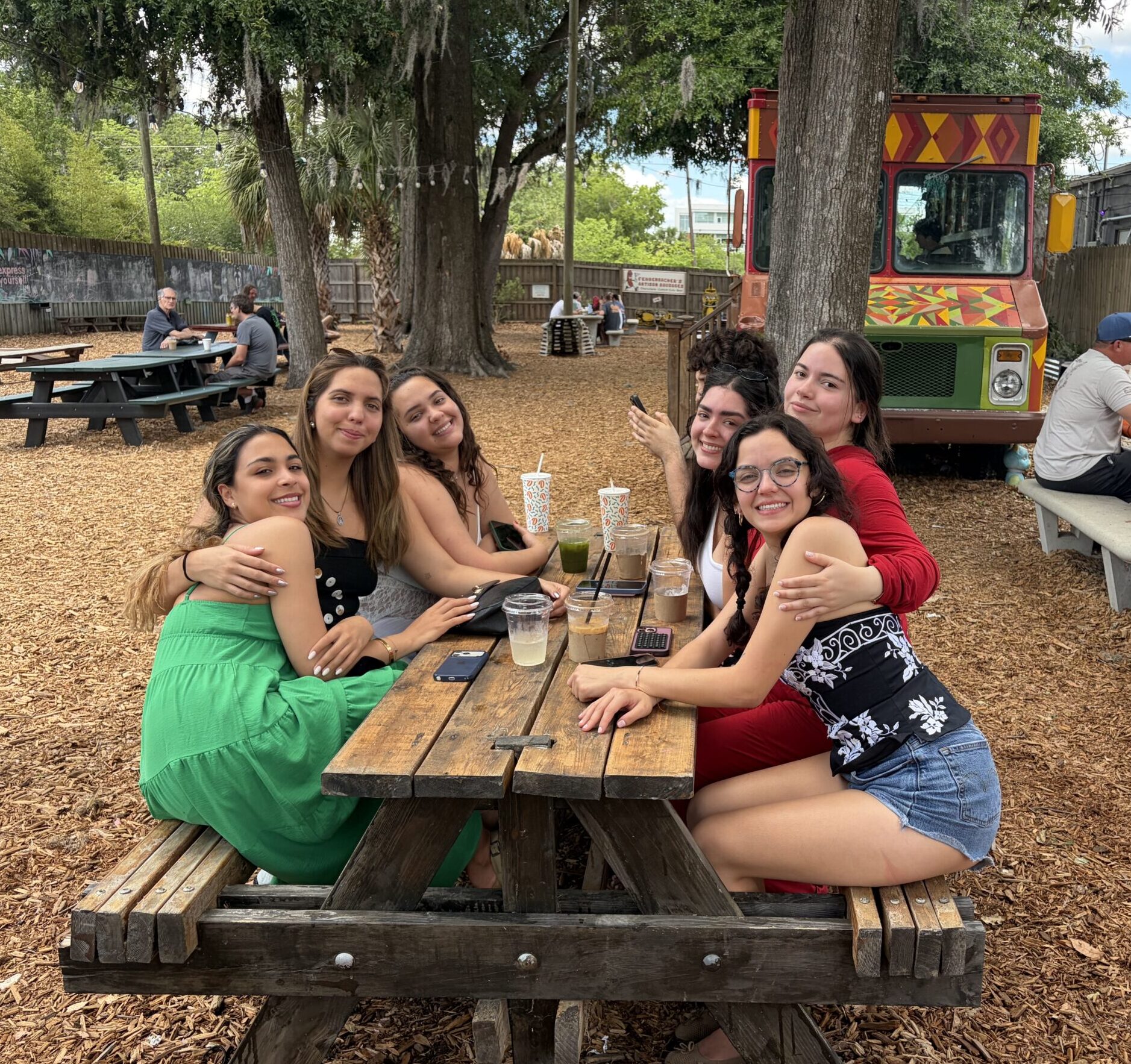 Ana Sofia y amigas sentadas en un picnic table smiling at the camera